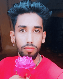 a man wearing a red shirt holds a pink flower