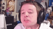 a man wearing headphones is making a funny face while sitting in front of a computer screen .