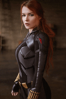 a woman with red hair is wearing a black suit with bullets on her belt