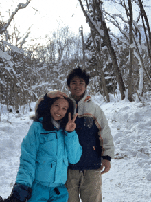 a man and a woman are standing in the snow and the woman is wearing a blue jacket