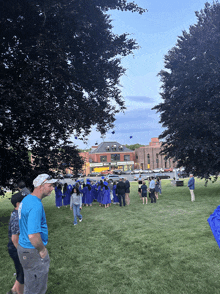 a group of people are gathered in a grassy field watching a graduation ceremony