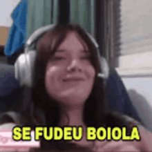 a woman wearing headphones is smiling and says se fudeu boiola in yellow letters .