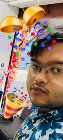 a man wearing glasses and a party hat is surrounded by confetti and ribbons