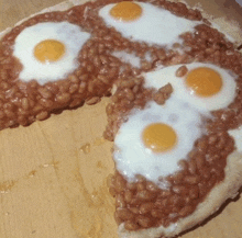 a pizza with beans and eggs on a wooden surface