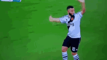 a soccer player is dancing on the field while wearing a white shirt and black shorts .