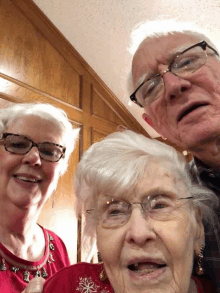 a man and two women are posing for a picture with an older woman wearing glasses