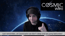 a man wearing headphones is pointing at the camera in front of a cosmic wire sign