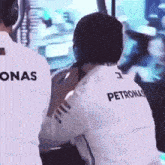 a man wearing a petronas shirt is sitting in front of a monitor