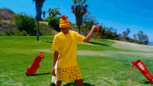 a man in a yellow shirt and polka dot shorts is standing on a golf course holding a golf club