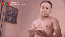 a shirtless man is holding a cell phone and says " dương thiên dậy con " in a foreign language