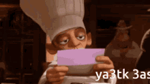 a man in a chef 's hat is looking at a piece of paper with the words ya3tk 3as below him