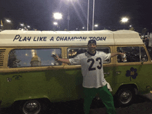 a man in a jersey with the number 23 stands in front of a green van