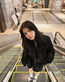 a girl is standing on an escalator in a mall .