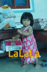 a little girl in a pink dress is standing in front of a pile of diapers and the word lalala is on the floor behind her