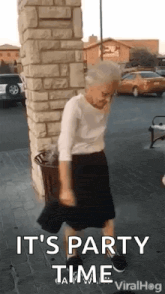 an elderly woman is dancing in front of a brick building .