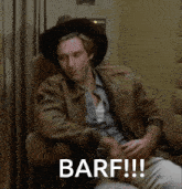 a man wearing a cowboy hat is sitting in a chair with the words barf written on the screen