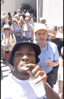 a man wearing a bucket hat is smoking a cigarette in front of a crowd