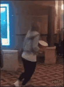 a woman is dancing in a room with a drum in her hands .