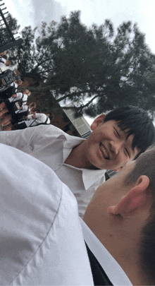 a boy in a white shirt is smiling while standing next to another boy in a white shirt