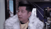 a man wearing a fur coat is standing in a room .