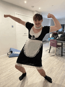 a man in a maid costume flexes his muscles in front of a blue laundromat bag