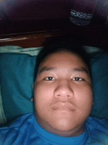 a young man in a blue shirt is laying in bed