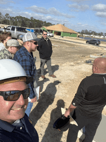 a group of men wearing hard hats and sunglasses are standing in a field