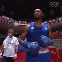 a man wearing boxing gloves and a white shirt that says eat britain is standing in a boxing ring .