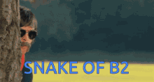 a man peeking out from behind a tree with the words " snake of b2 " above him