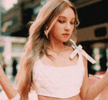 a woman wearing a white crop top with a white bow