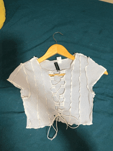 a white crop top with a lace up front is on a wooden hanger