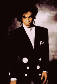 prince is wearing a black tuxedo with white polka dots and a white shirt .