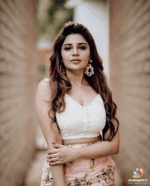 a woman wearing a white crop top and floral skirt poses for a photo with indiaglitz