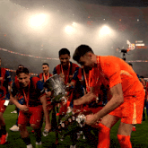 a group of soccer players are holding a trophy and one of them is wearing a jersey that says nike sport