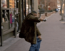 a man in a brown coat walking down a sidewalk