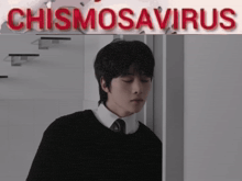 a man in a black sweater and tie stands in front of a sign that says chismosaurus