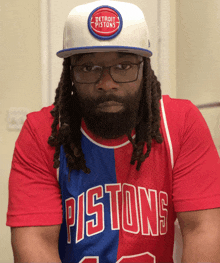 a man wearing a detroit pistons jersey looks at the camera