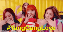 a group of girls are covering their mouths with their hands while standing next to each other in front of a yellow background .