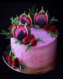 a pink cake with raspberries figs and leaves on top