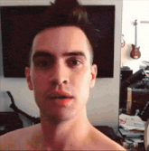 a man without a shirt is taking a selfie in front of a tv