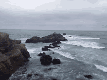 a rocky shoreline with waves crashing against the rocks on a cloudy day