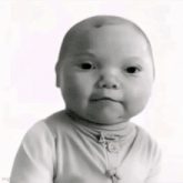 a black and white photo of a baby wearing a white sweater