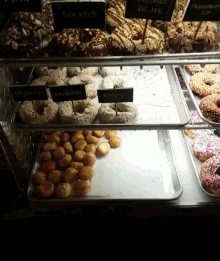 a variety of donuts are displayed in a display case with a sign that says ' sprinkles ' on it