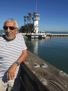 a man wearing sunglasses stands on a pier in front of a sign that says ponder island