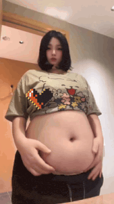 a woman with a very large belly is wearing a crop top .