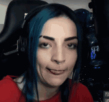 a woman with blue hair is wearing headphones and making a funny face .