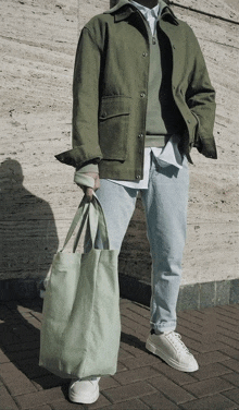 a man wearing a green jacket is holding a green bag