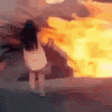 a woman is walking in front of a fire .