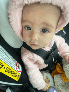 a baby is sitting in a car seat with a warning label