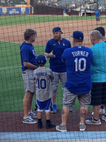 a boy wearing a turner 10 jersey talks to a group of men